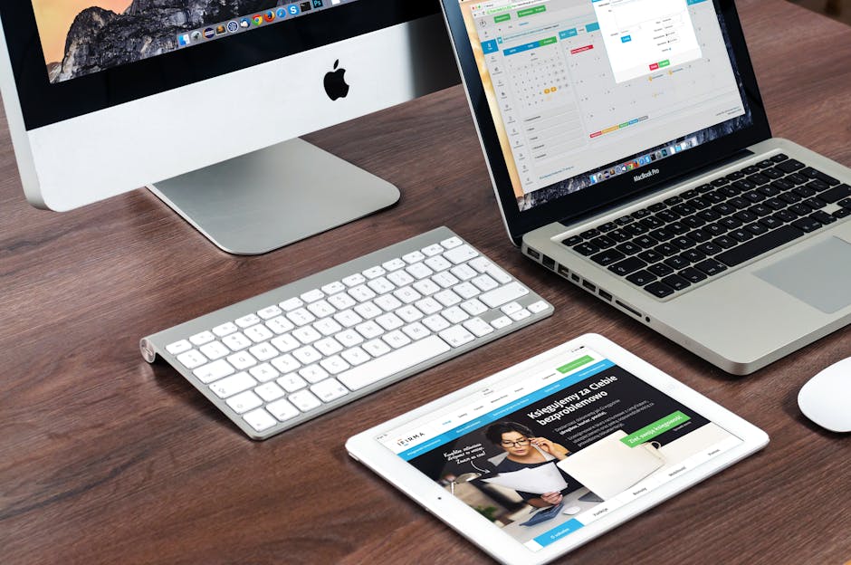 A sleek office desk setup featuring Apple devices: iMac, MacBook, and iPad